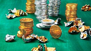 A photo of stacks of chocolate coins on a green background