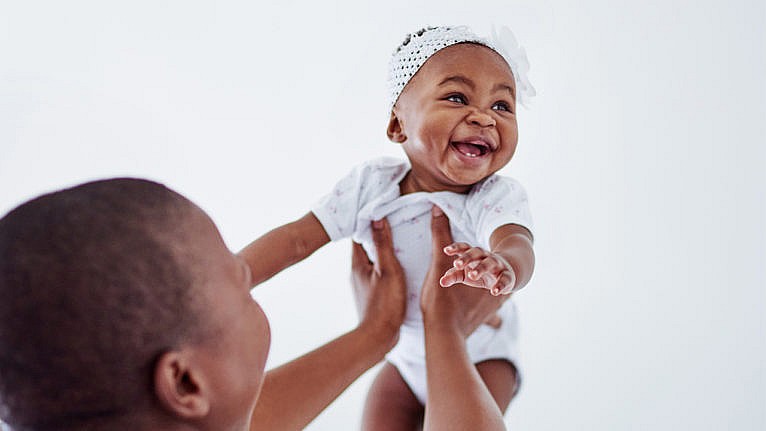Photo of a parent holding up a laughing baby