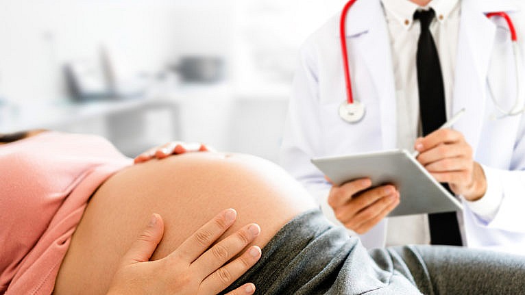 Photo of a pregnant person getting checked on by a doctor