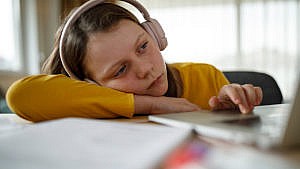 Photo of a kid looking bored while on the computer doing virtual learning