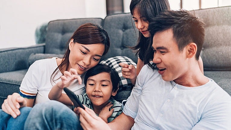 A family playing a game together on a smartphone.