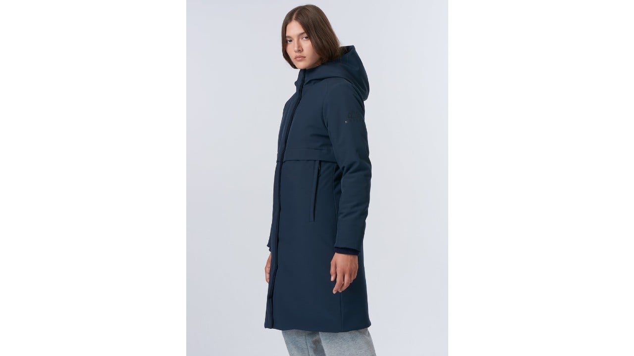 Photo of a woman wearing the Norden Inga Bonded Parka in navy blue. The parka goes down to about her knee and has a hood