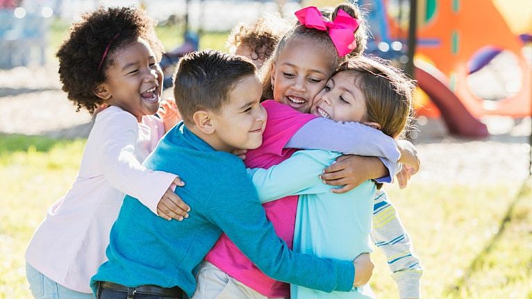 A small group of kids hug each other.