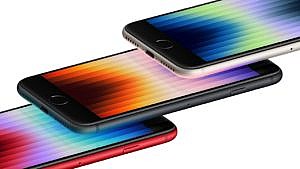 Image shows three iPhones in Midnight (navy), Starlight (off white) and Red laying horizontally on a white background with abstract colourful graphics showing on each screen