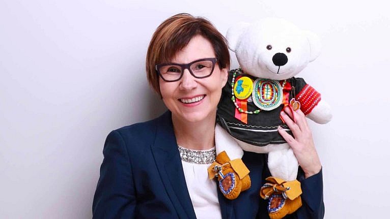 An image of Dr. Cindy Blackstock holding a stuffed white bear.