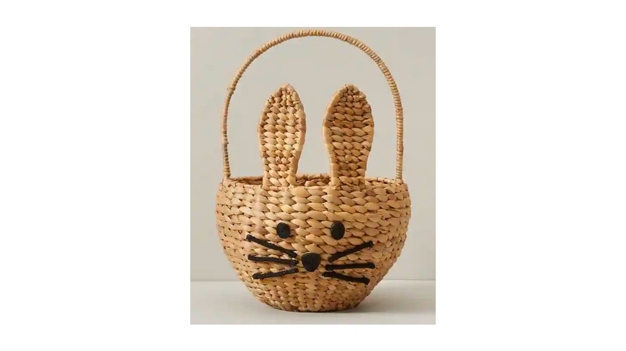A wicker Easter basket with bunny ears and black stitching for the face.