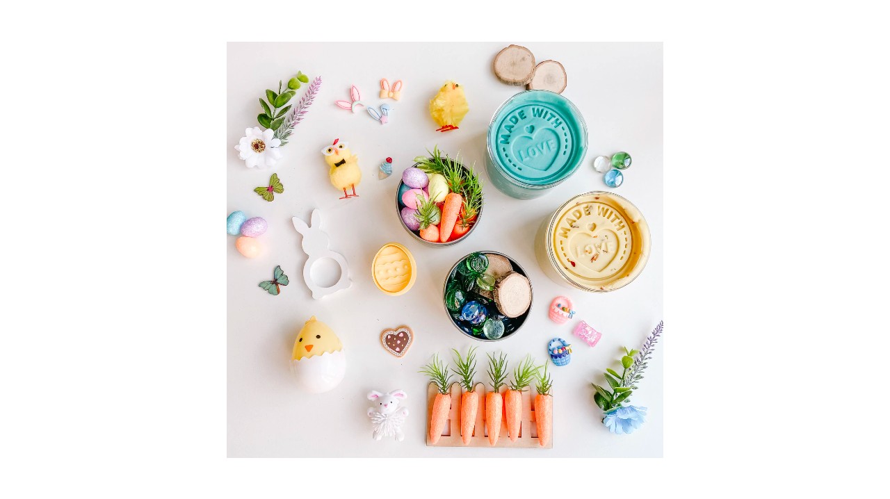 A flat lay of different coloured jars of playdough, sensory toys like carrots and bunny shaped cookie cutters.