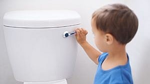 An image of a young boy flushing a toilet.