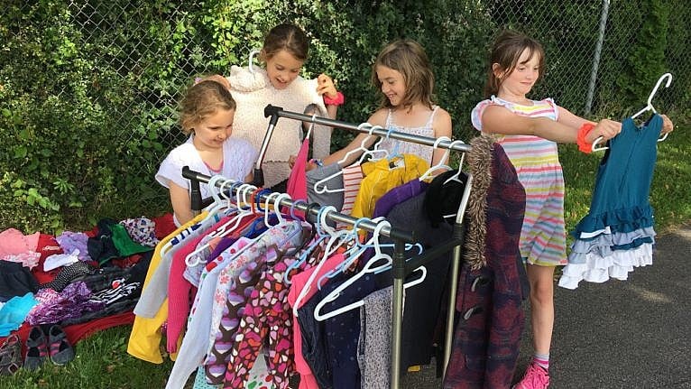 An image of young girls looking at clothes on a rack.