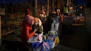 A woman holds her child in her arms while talking on the phone at the border of Ukraine and Romania.