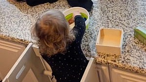 An image of a toddler sorting toys from one box to another.