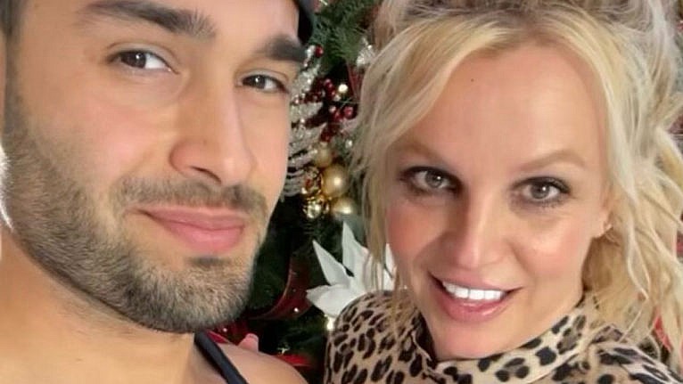 Sam Asghari and Britney Spears pose together in front of their Christmas tree in an Instagram photo