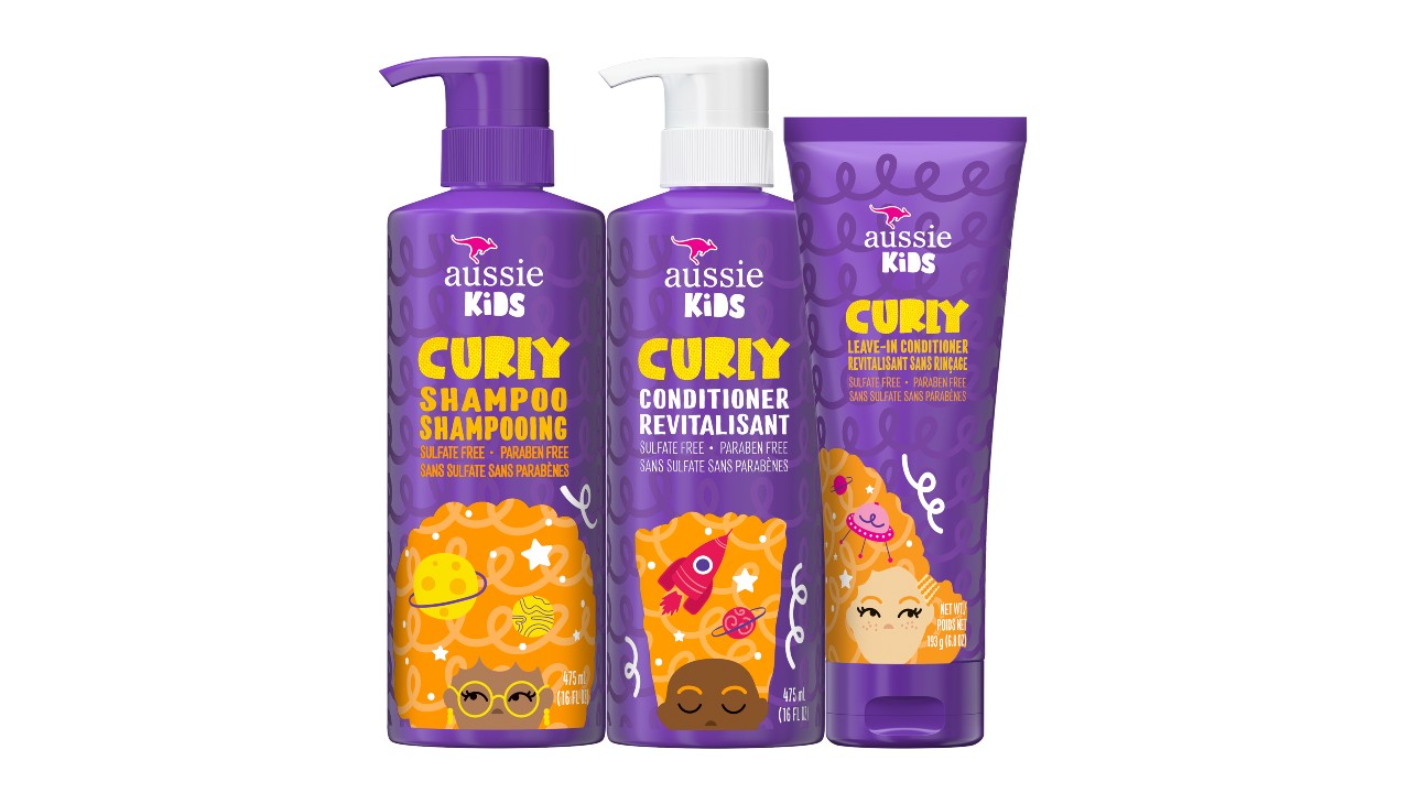 An image of three purple and orange bottles, one containing shampoo, another with conditioner, and the last with leave-in conditioner.