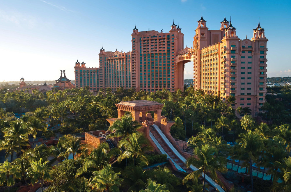 A waterpark slide and the hotel rise up from dense palm trees at Atlantis Paradise Island in the Bahamas