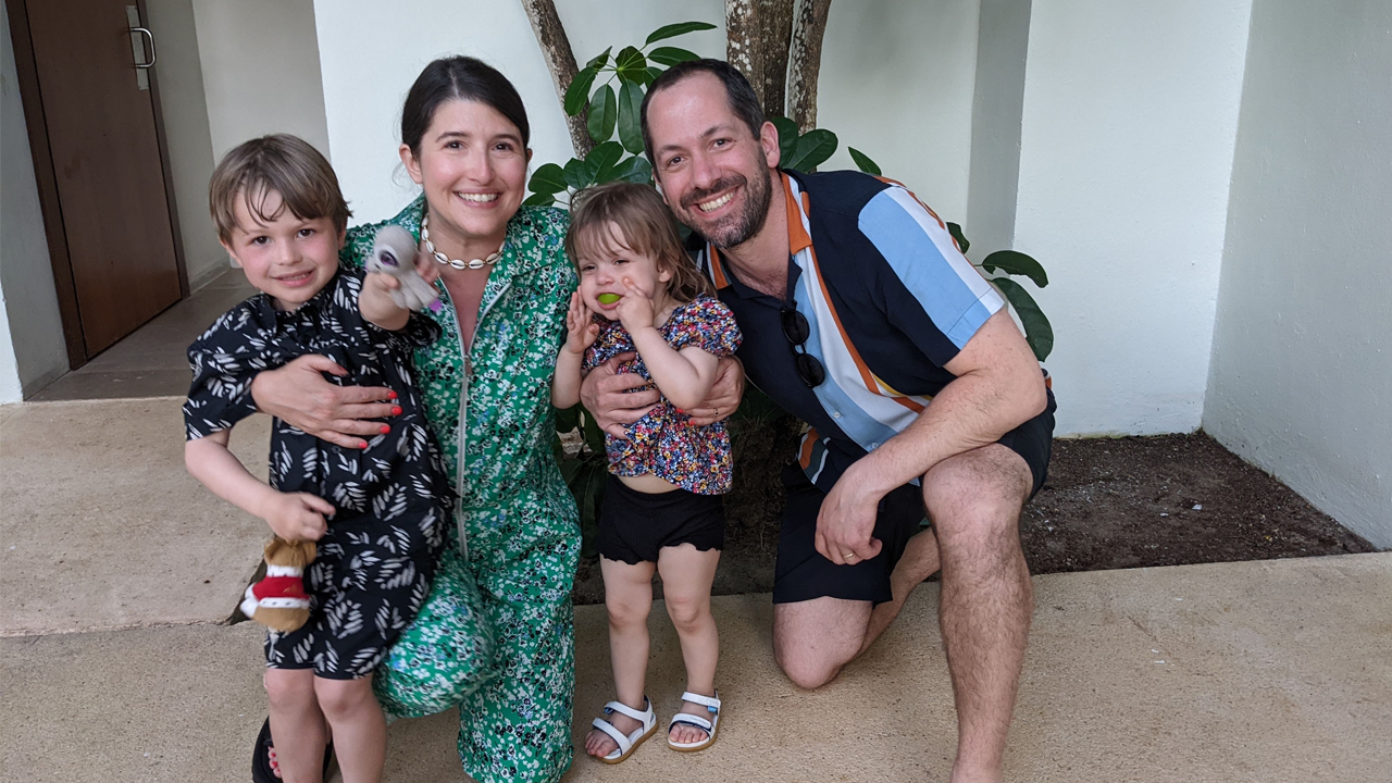 A woman and man pose with two children all dressed in vacation clothing