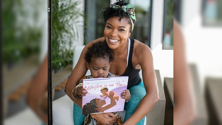 Gabrielle Union poses with her baby Kaavia holding their book 'Welcome to the Party'
