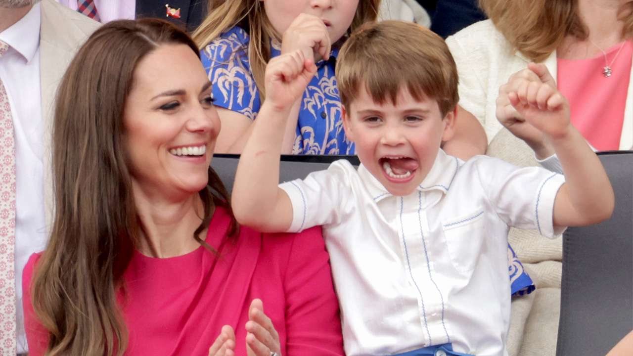 Prince Louis raises his arms with his tongue out as his mother giggles at the platinum anniversary contest