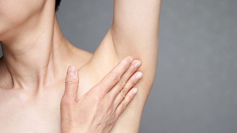 A woman's hand covering her bare armpit, where yeast infections can occur