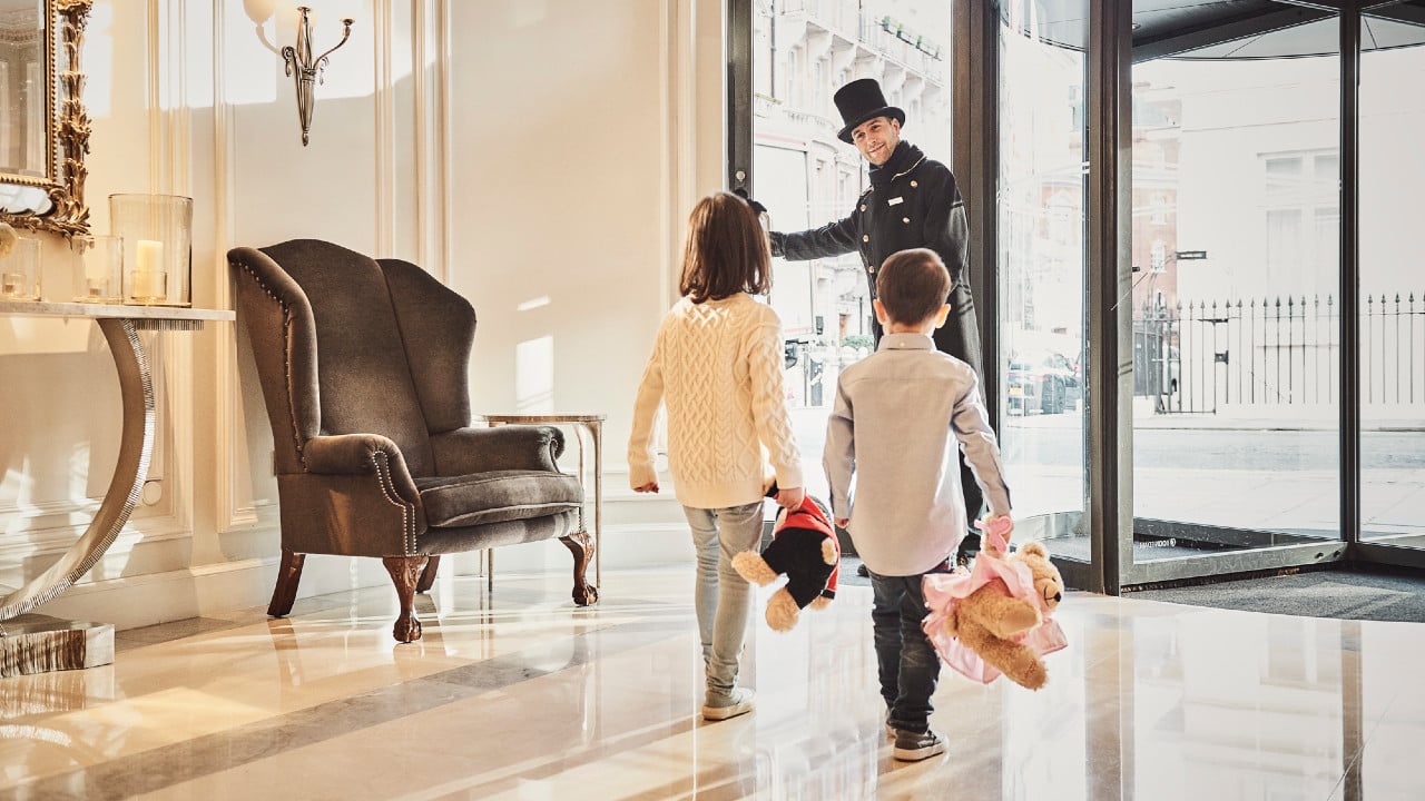 Two children carrying teddy bears inside the lobby of the London Marriott Hotel
