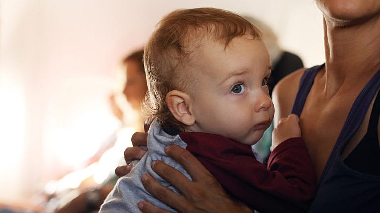 A mother holds her baby while traveling on an airplane