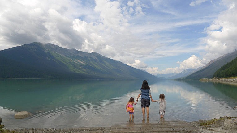 A mother and two kids stands in front of Moose Lake in British Columbia