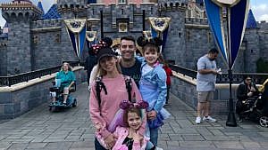 The author with her partner and two kids wearing Mickey ears at Dinseyland