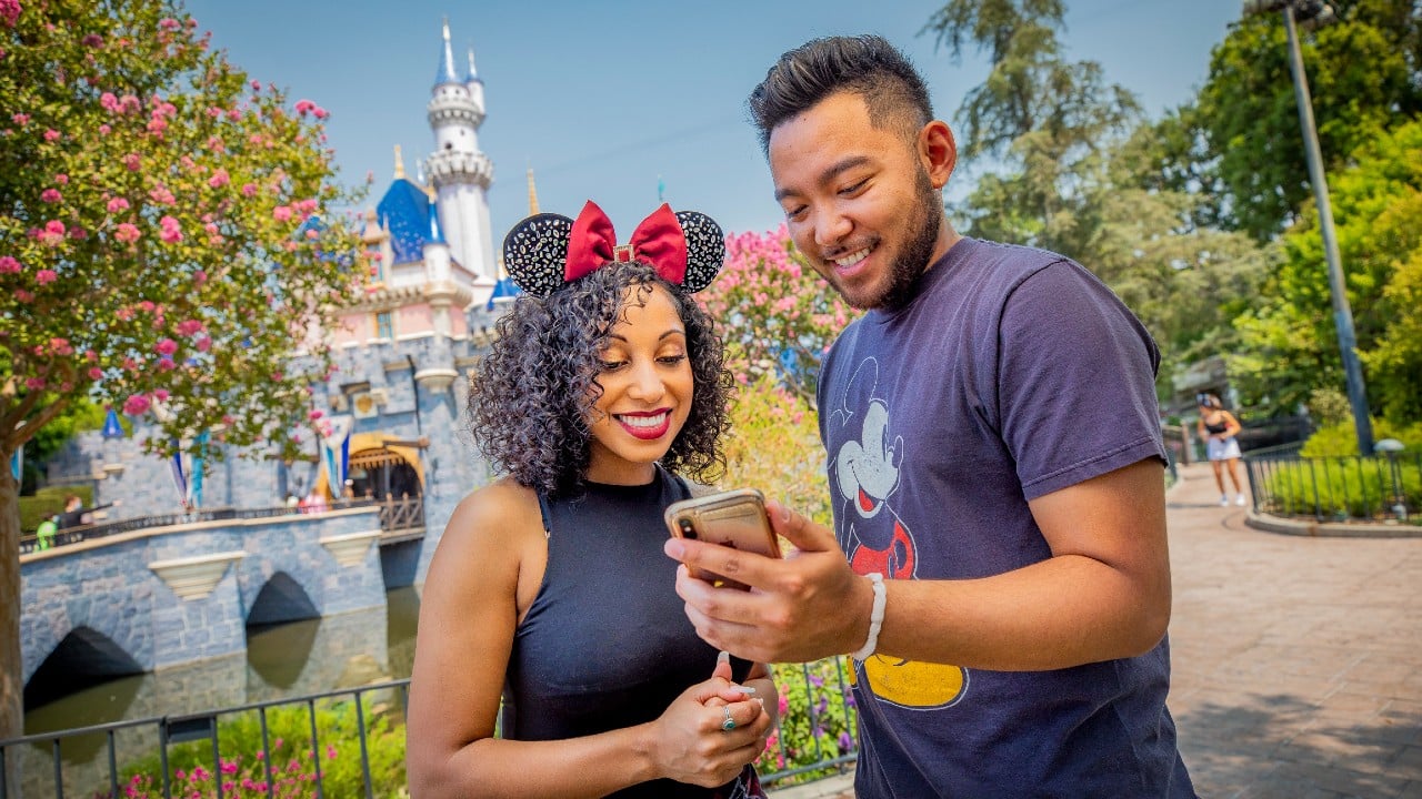 A man and woman at Disneyland looking at a phone
