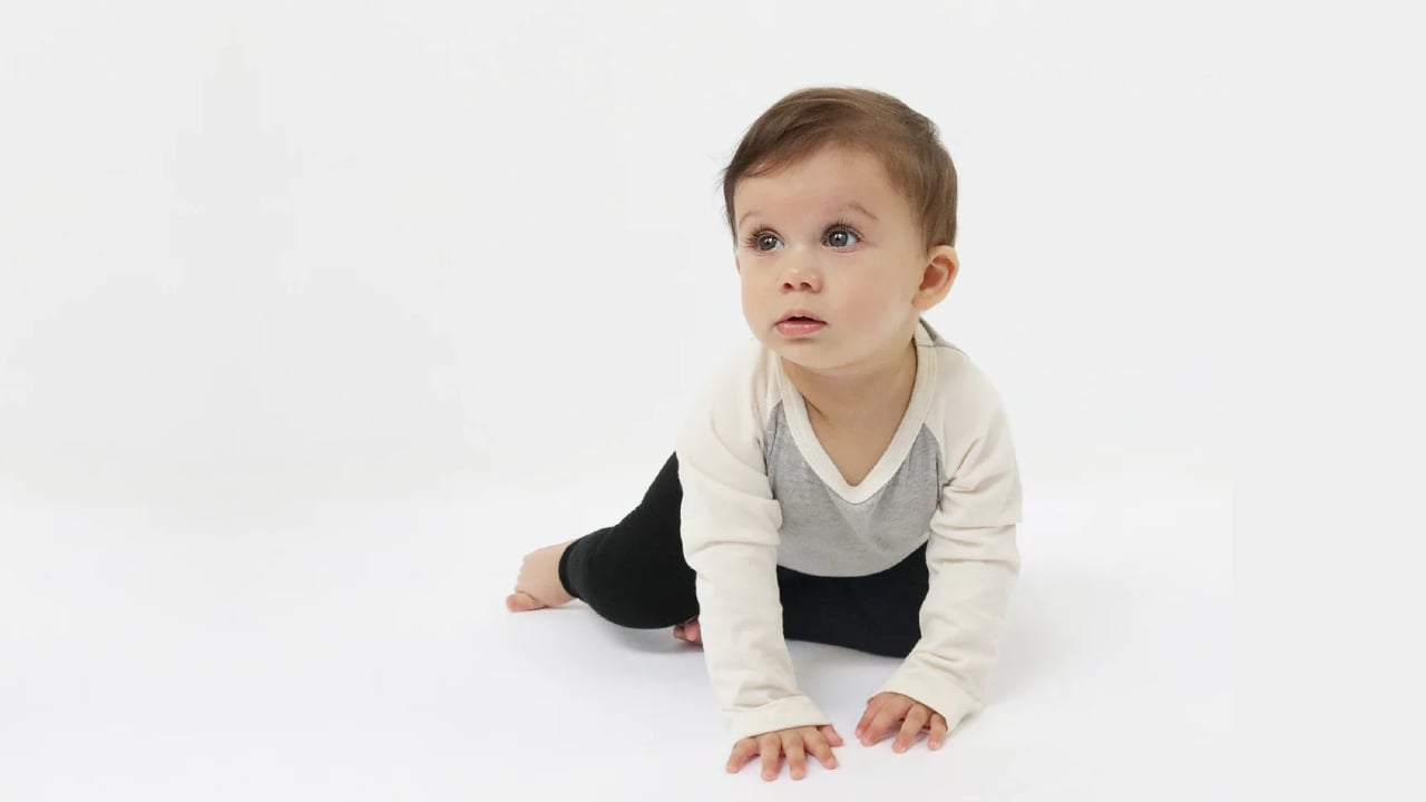 A child wearing a gender-neutral onesie and pants from Mini Mioche