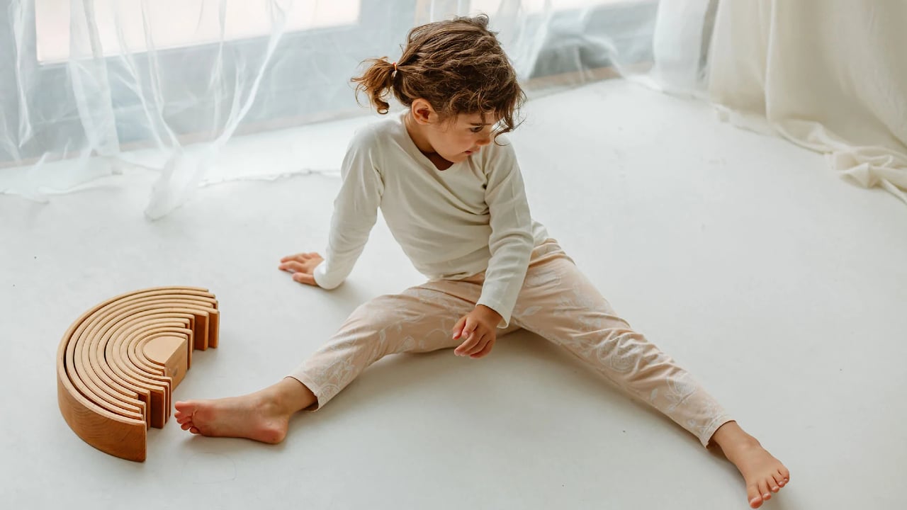 A child plays while wearing neutral leggings and a shirt from Nest Designs