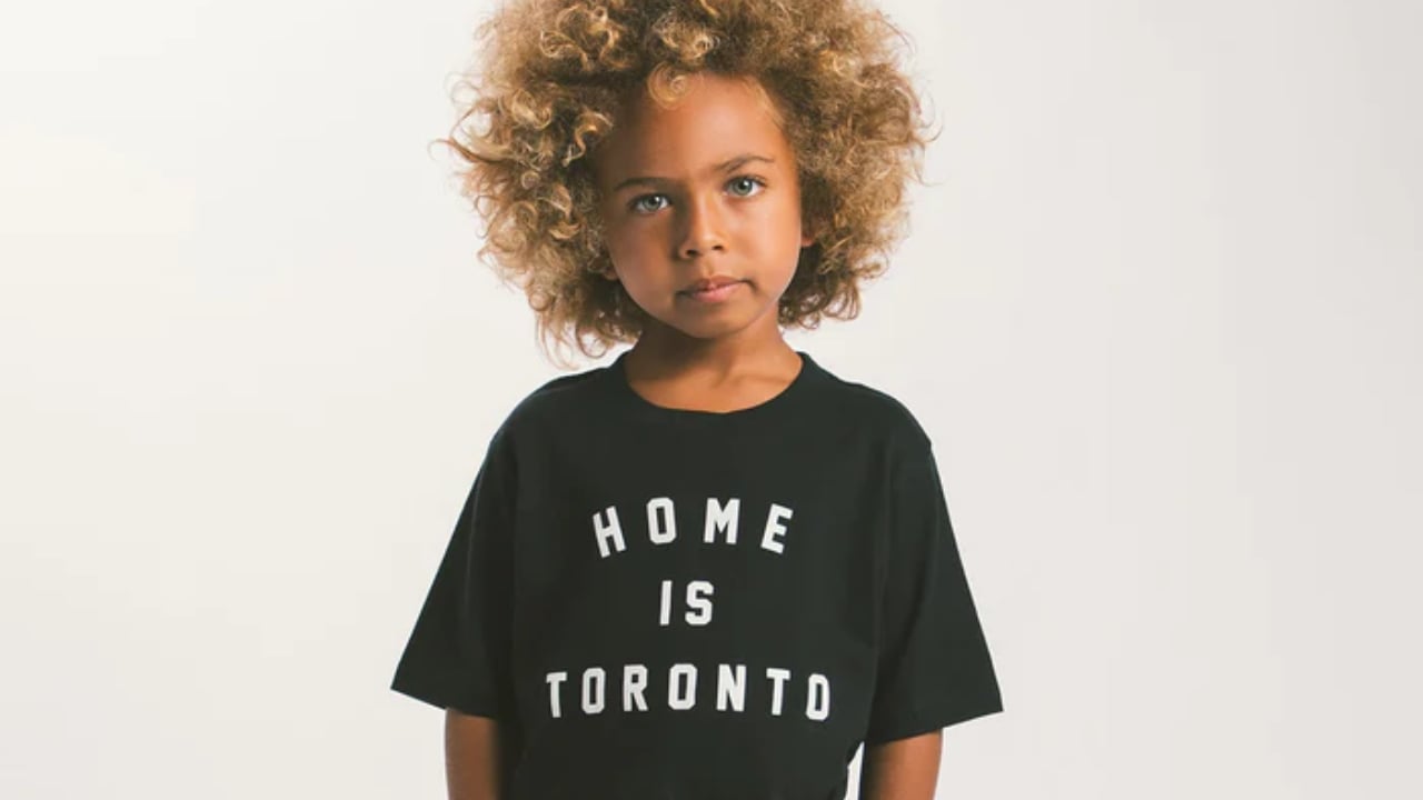 A child wearing a gender-neutral "Home is Toronto" t-shirt from Peace Collective
