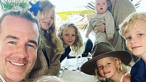 James Van Der Beek smiles for the camera at a restaurant with five of his six kids in the frame
