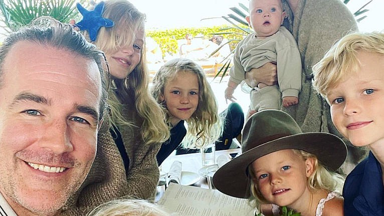 James Van Der Beek smiles for the camera at a restaurant with five of his six kids in the frame
