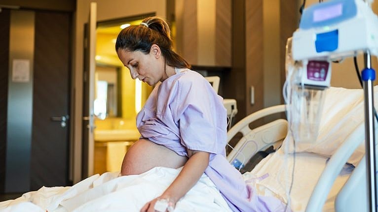Pregnant woman in a purple hospital gown preparing for delivery