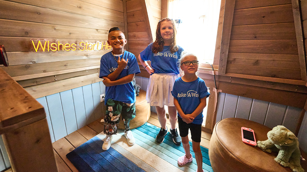 Three kids stand in the playhouse's upstairs loft area