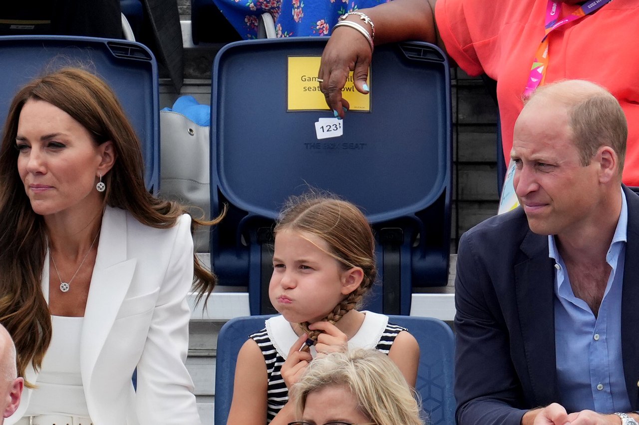 Princess Charlotte plays with her braided pigtails and puffs out her cheeks in the stands at the Commonwealth Games.