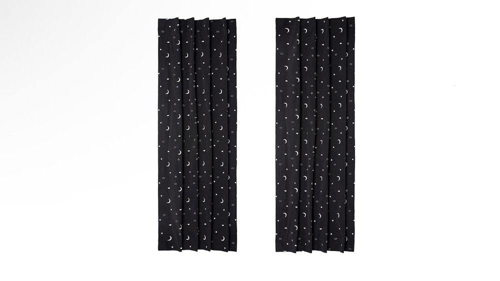 A pair of black Amazon Basics blackout curtains with moons and stars on them.
