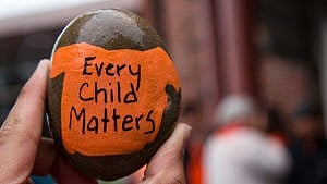 A close-up shot of a rock featuring a painting of an orange T-shirt with the words "Every child matters."