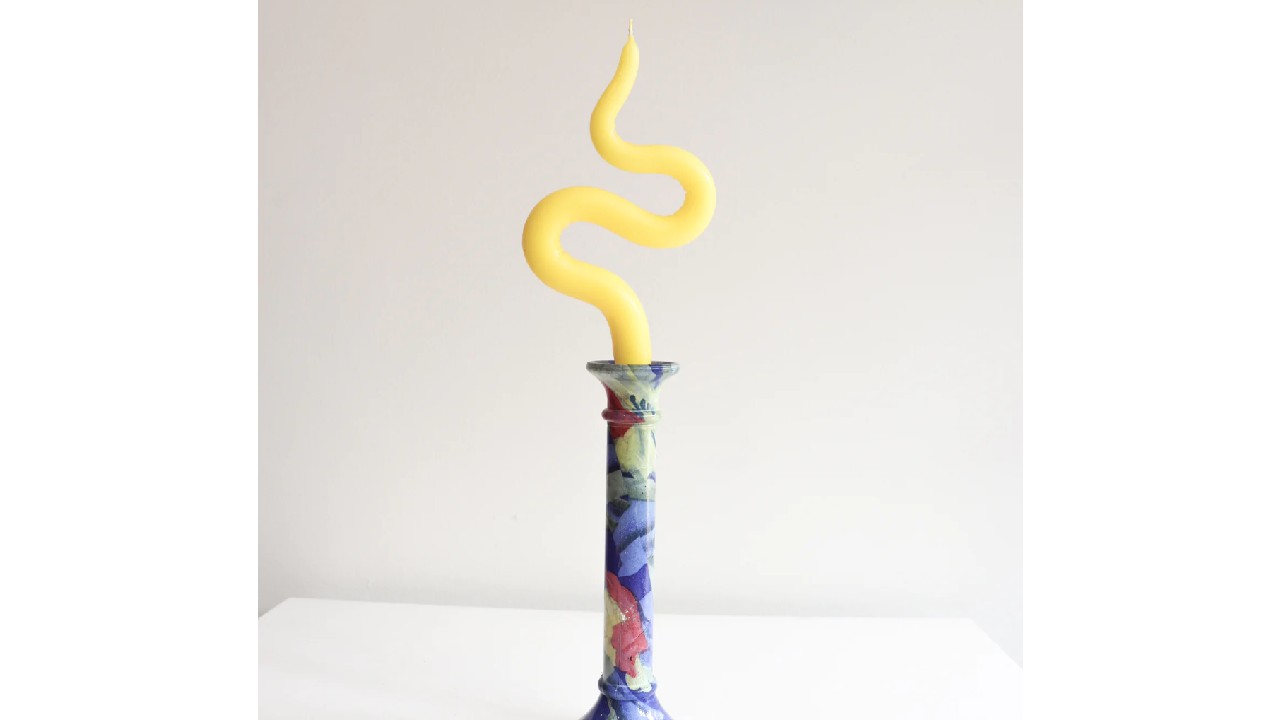 curved yellow candle on floral candle stick holder