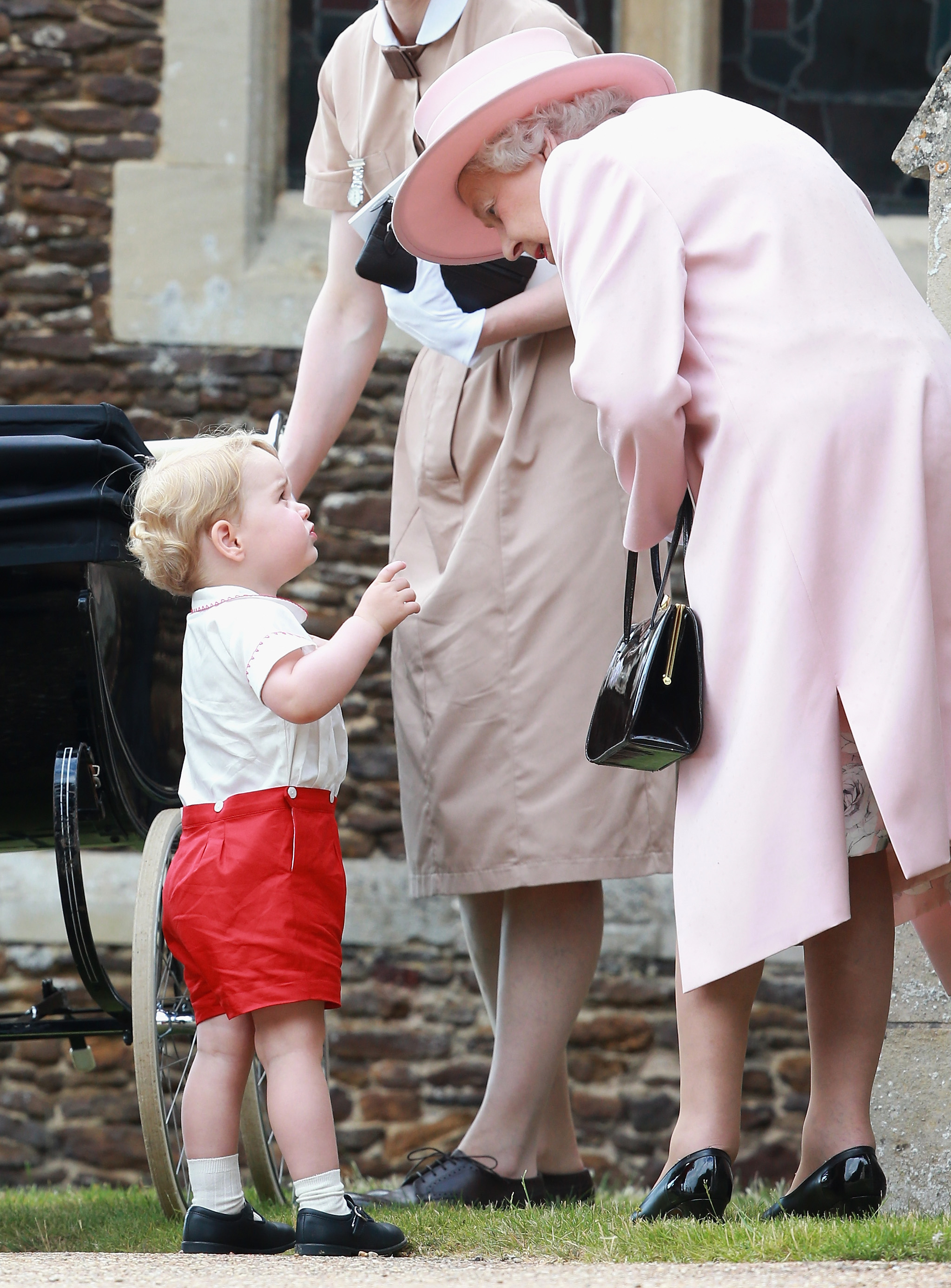Malý chlapec princ George sa rozpráva s kráľovnou na krste princeznej Charlotte.
