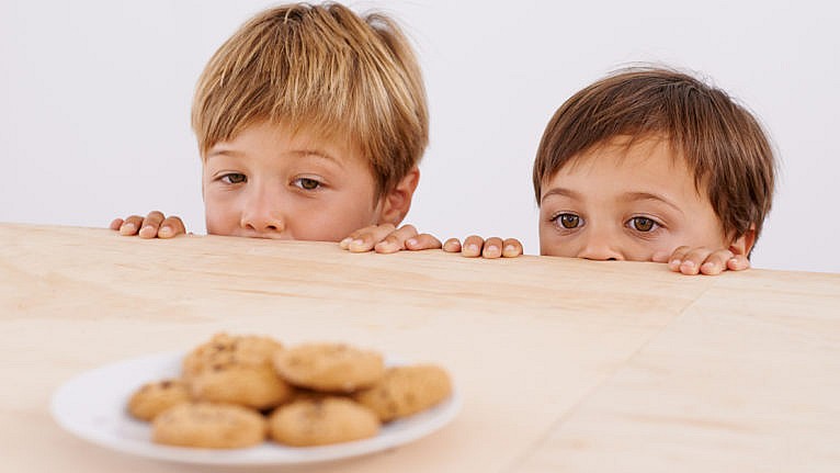 Two young boys looking at a plate of freshly baked cookies