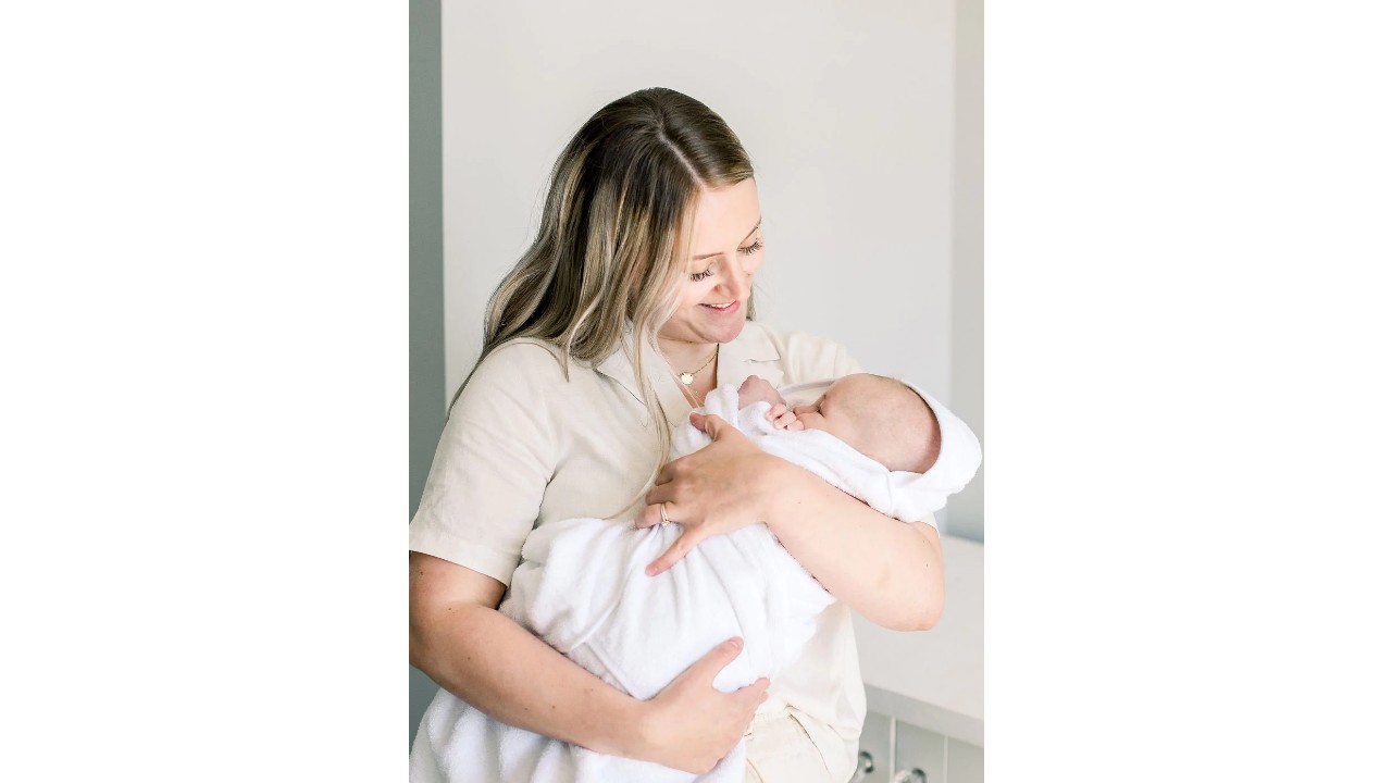 a mother holds a baby wrapped in white Fuzzy Sprout towel