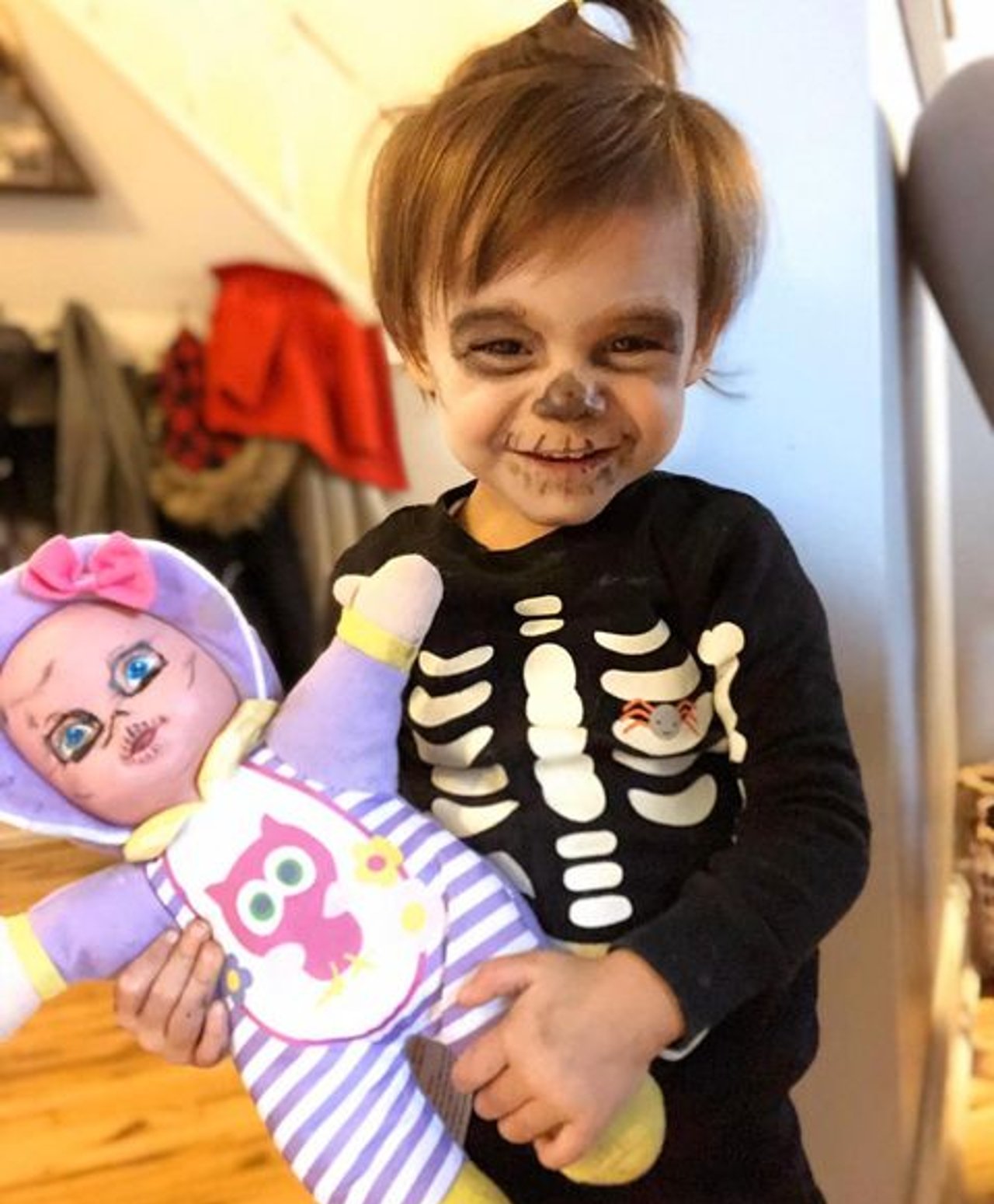 A picture of Noe holding a doll while dressing up as a skeleton.