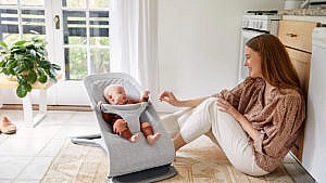 Lifestyle image of mom interacting with baby in a bouncer