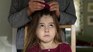 A mother checking her daughter's hair for head-lice using a nit comb